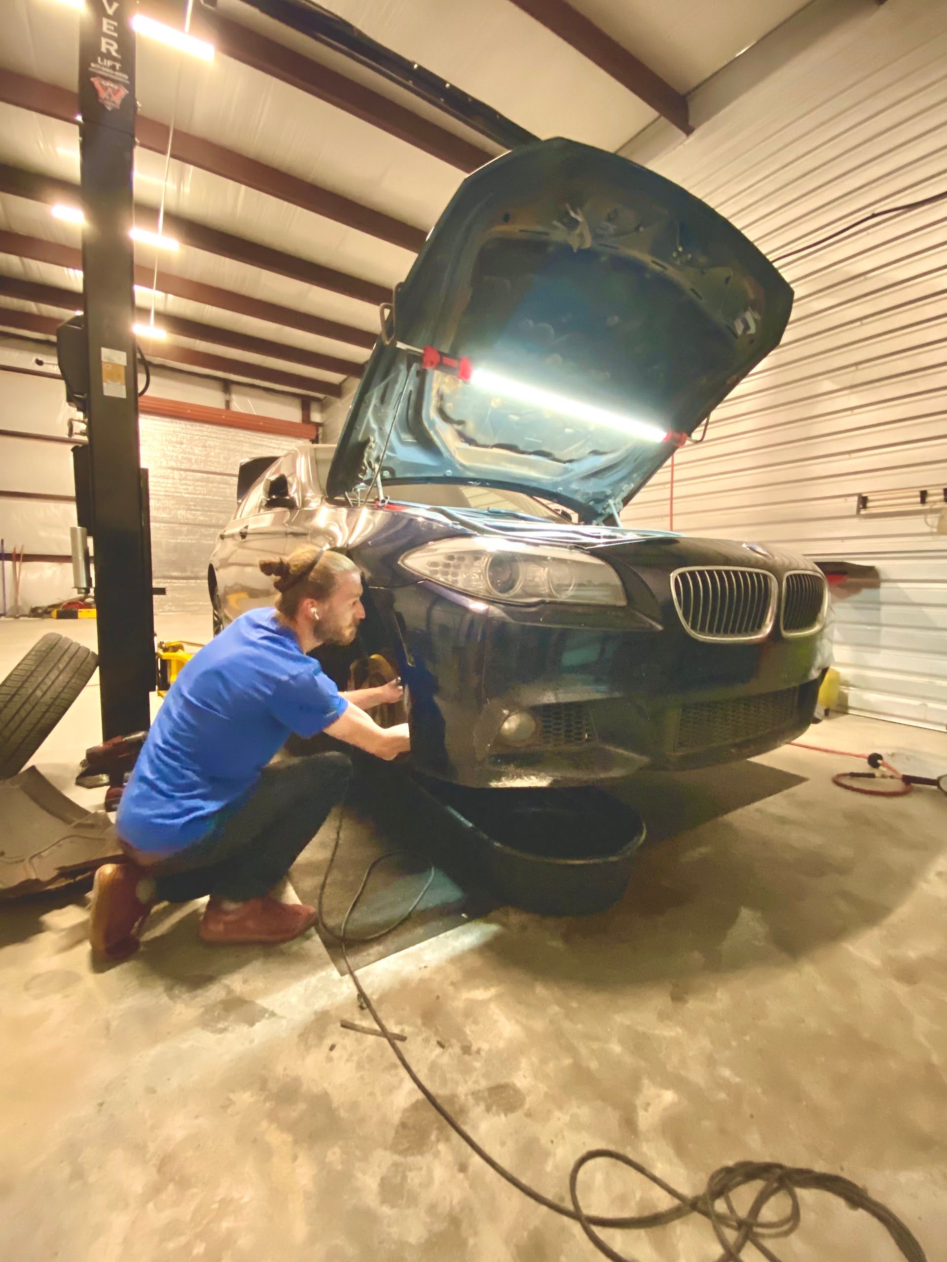 Technician Repairing A Black BMW With The Hood Open | TLC Automotive