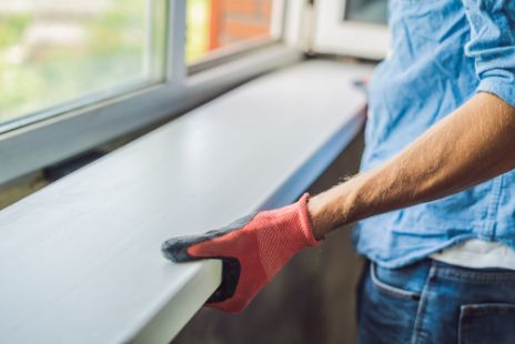 A Man Wearing Gloves is Cleaning a Window Sill — Darwin Glass in Yarrawonga, NT