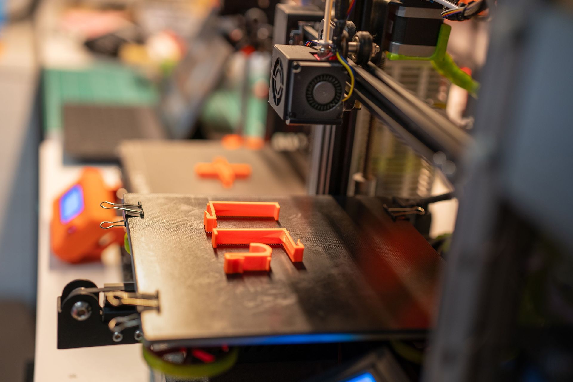 3D printer producing small orange plastic parts