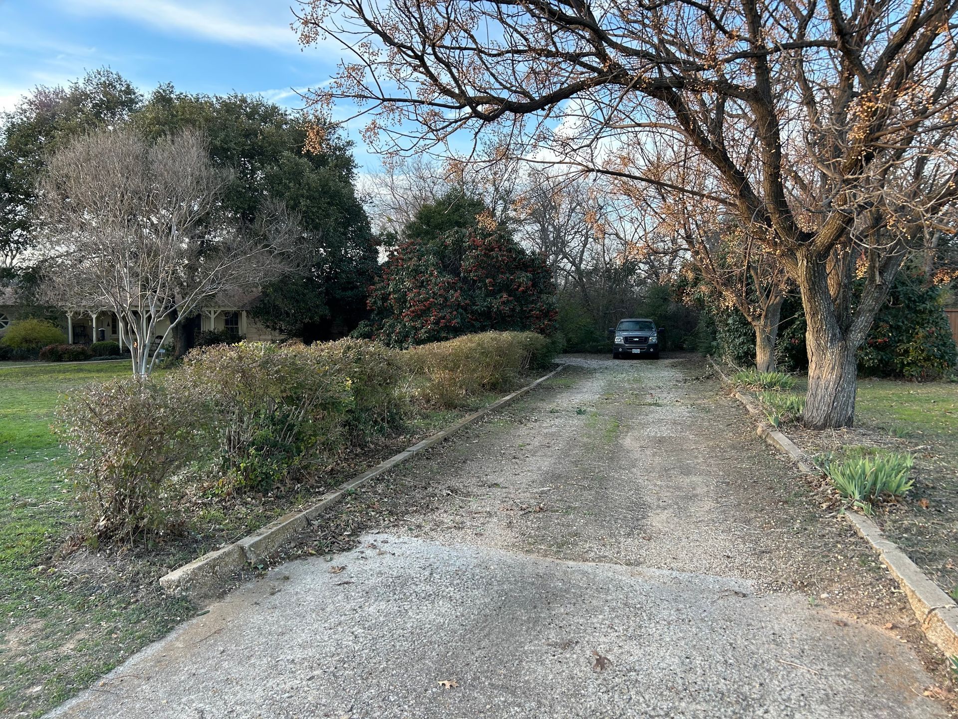 A car is parked on the side of a gravel road.