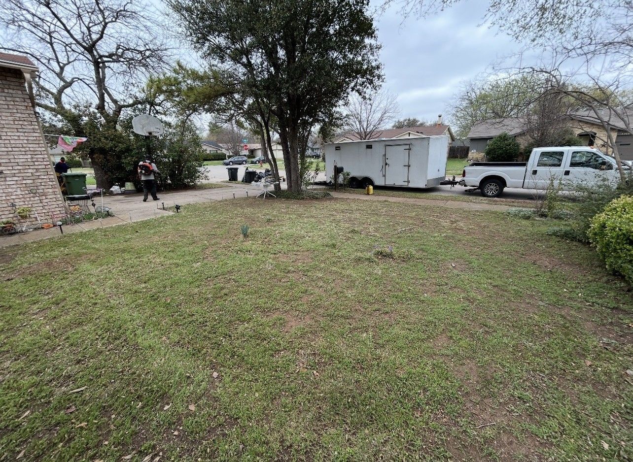 Front yard with a grassy lawn, trees, and a white pickup truck parked beside a small house.