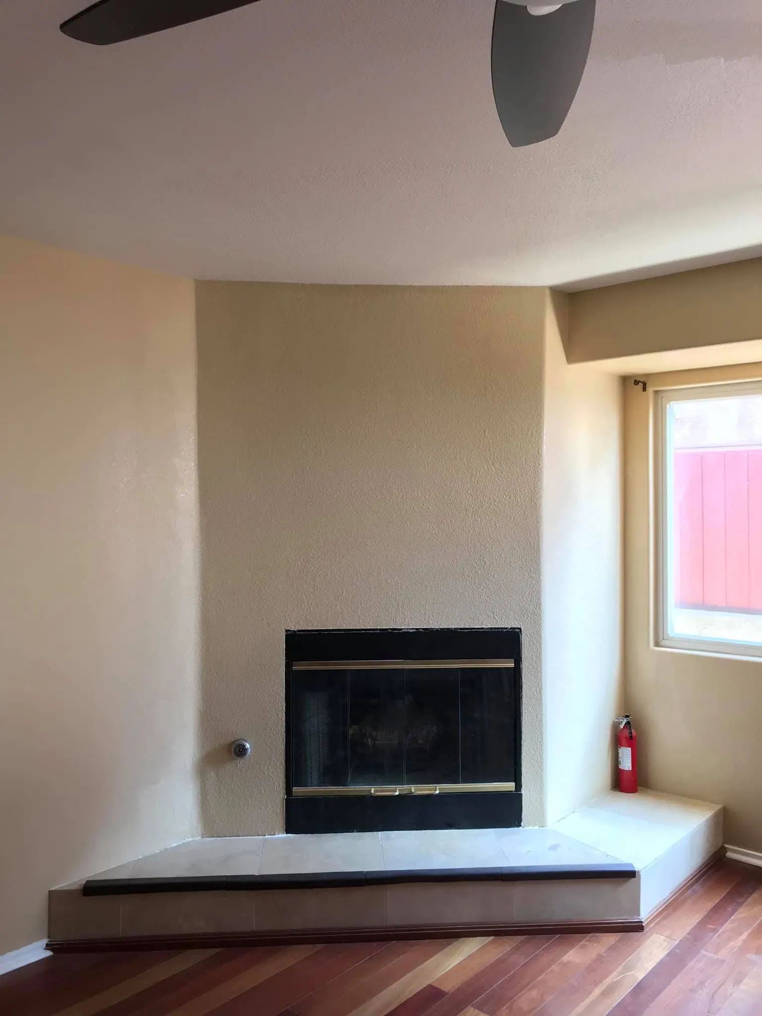 Fireplace with black surround, beige wall, and wood floor.