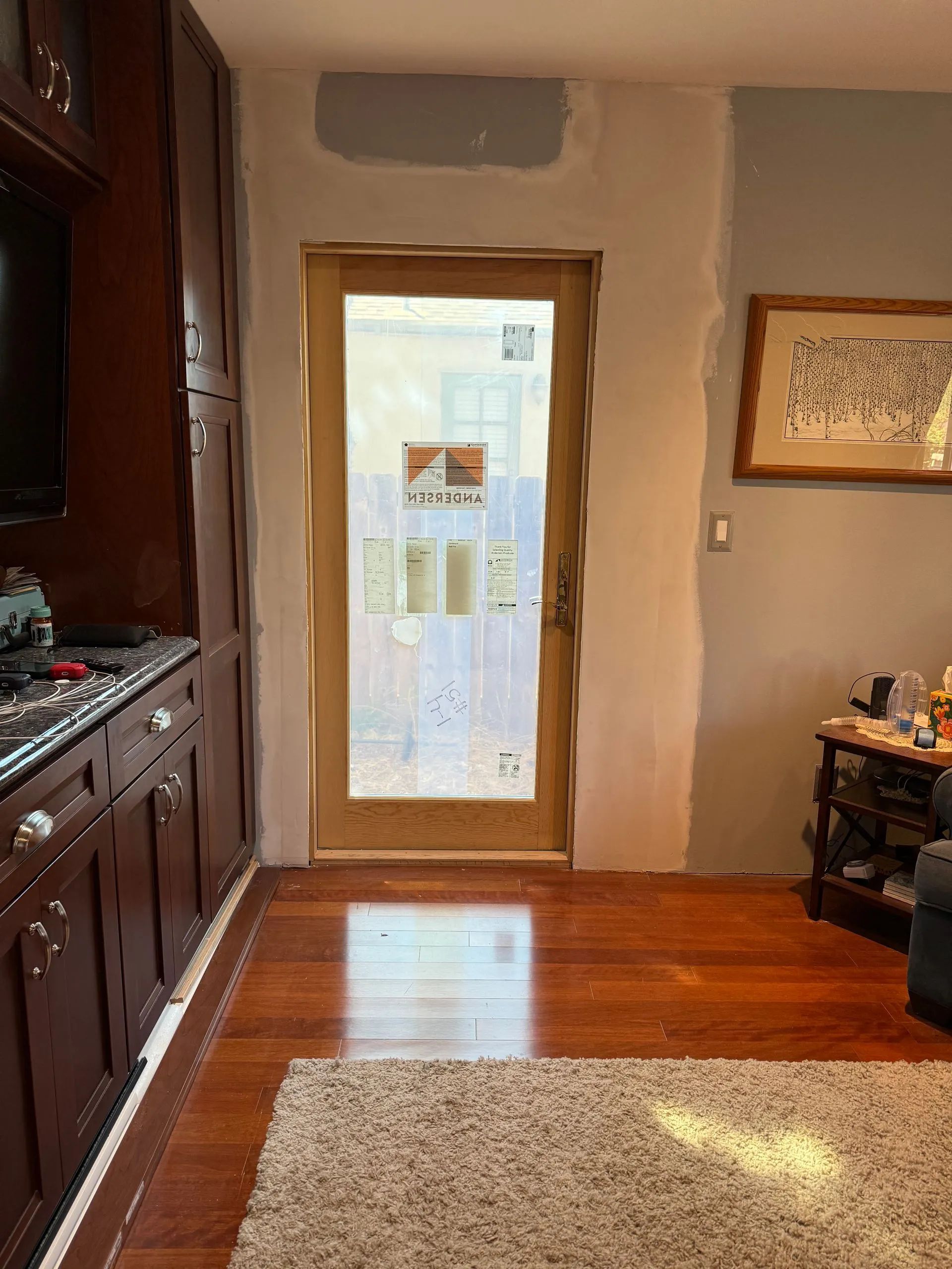 A wood-framed door with a frosted glass insert, set in a partially painted interior wall next to dark wood cabinets.