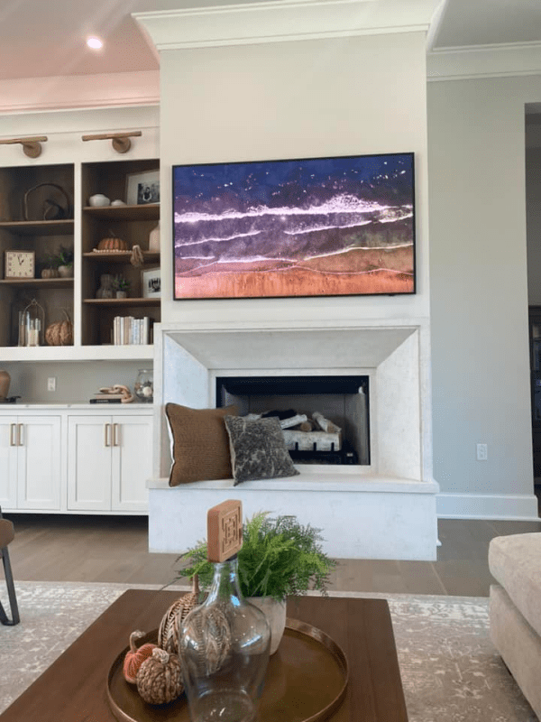 Living room with a white fireplace, wall art above it, built-in shelves, and a coffee table in front