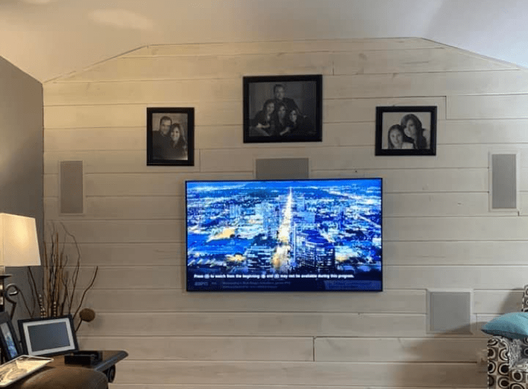 Living room wall with mounted TV, framed photos, and warm lighting