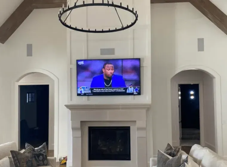 Living room with a wall-mounted TV above a fireplace and two tall arched doorways.