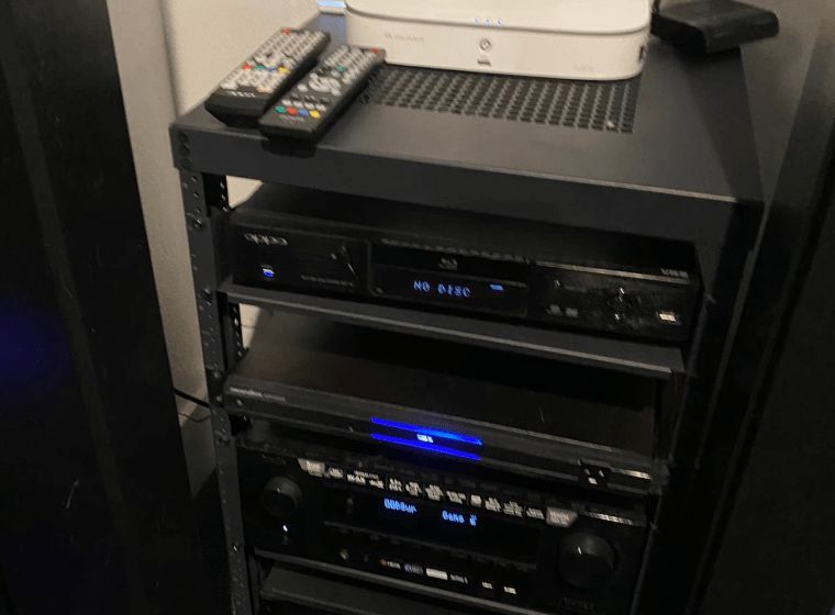 Black media cabinet with several AV components and remote controls on top