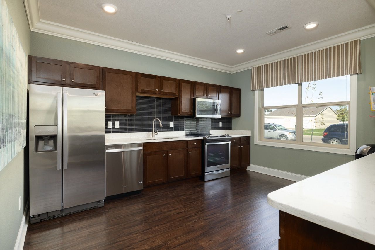 Kitchen in an apartment with dark wood cabinets, stainless steel appliances, and a window.