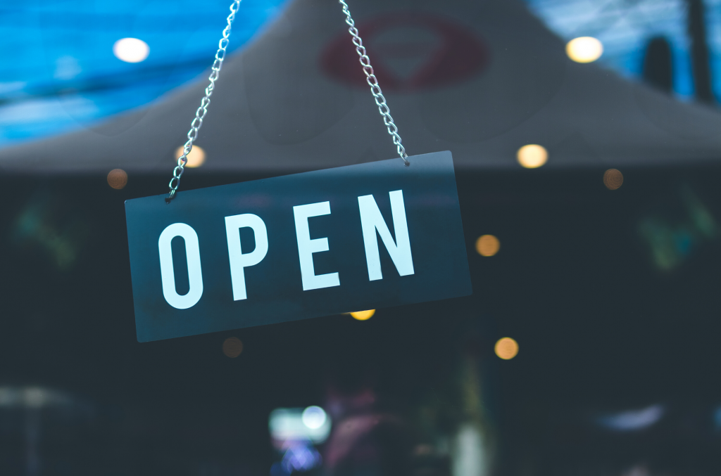 A sign that says open is hanging from a chain.