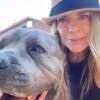 Woman in hat with dog, both close-up; woman smiling, dog looking at camera.