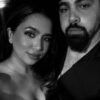 A couple in black and white, the woman smiling and the man with a beard, looking serious.