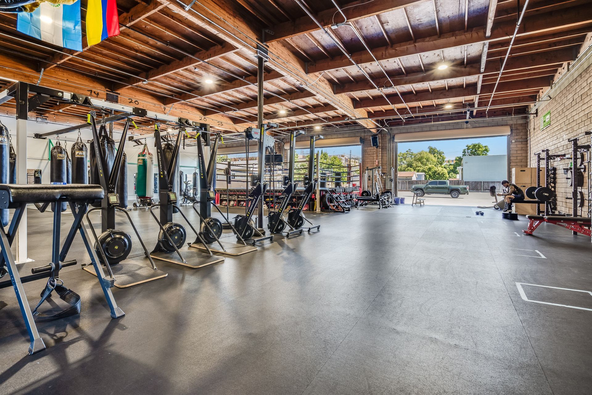A spacious gym with various workout equipment, including rowing machines and weight racks, located indoors.