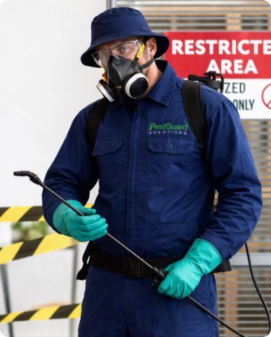 Worker in blue coveralls and respirator spraying in a restricted area