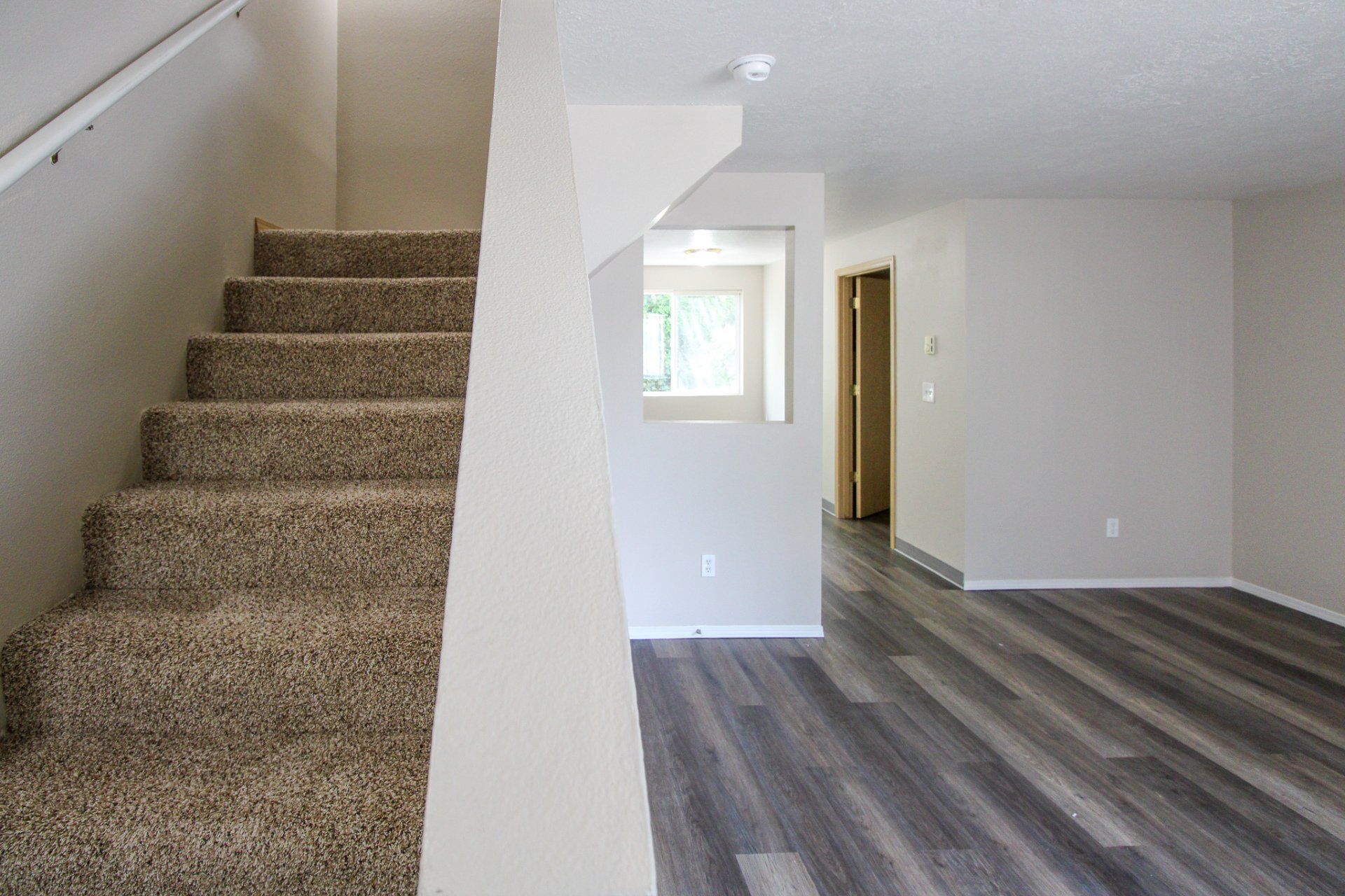 A living room with hardwood floors and stairs leading up to the second floor.