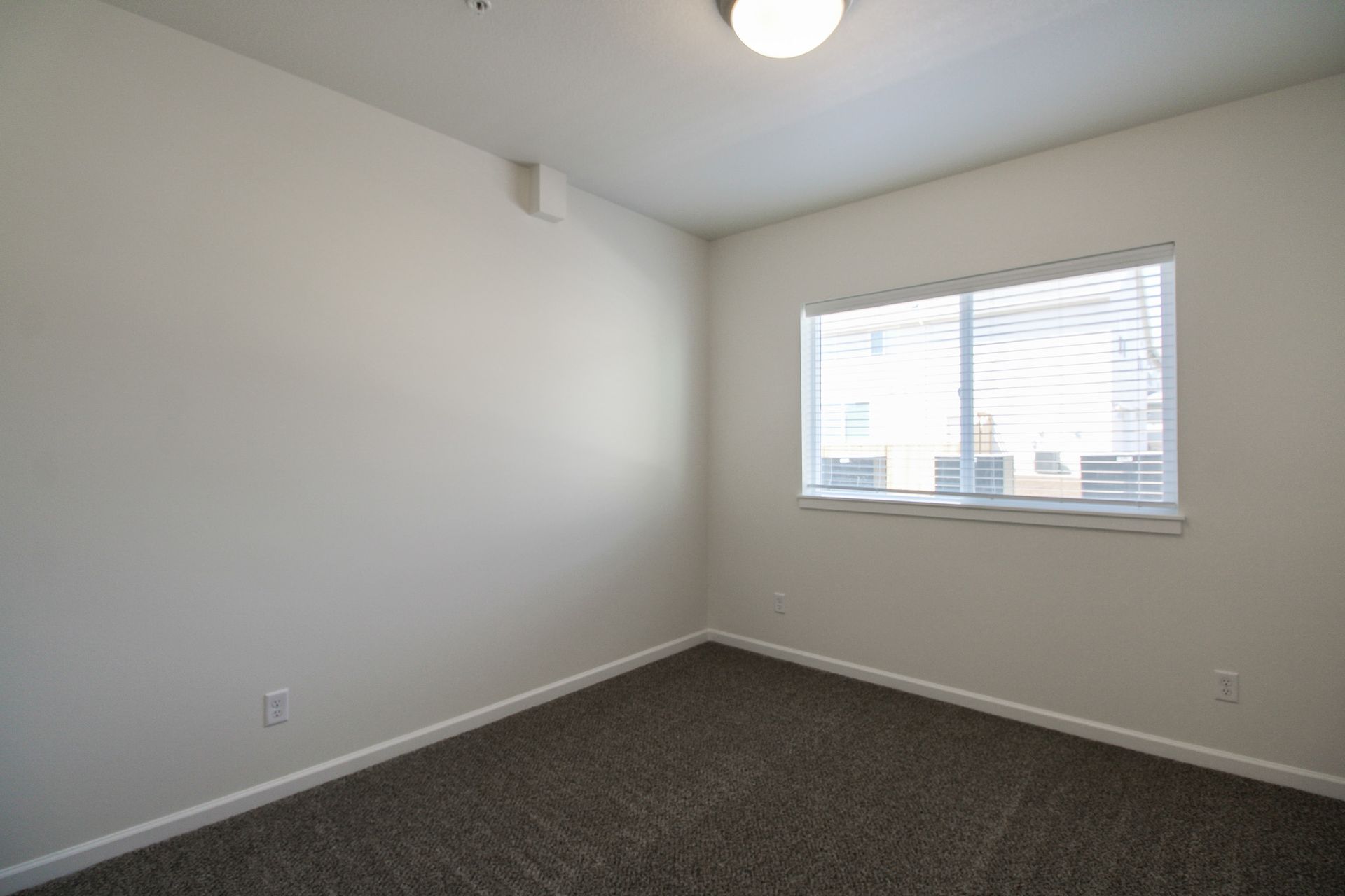 An empty bedroom with a window and a ceiling fan.