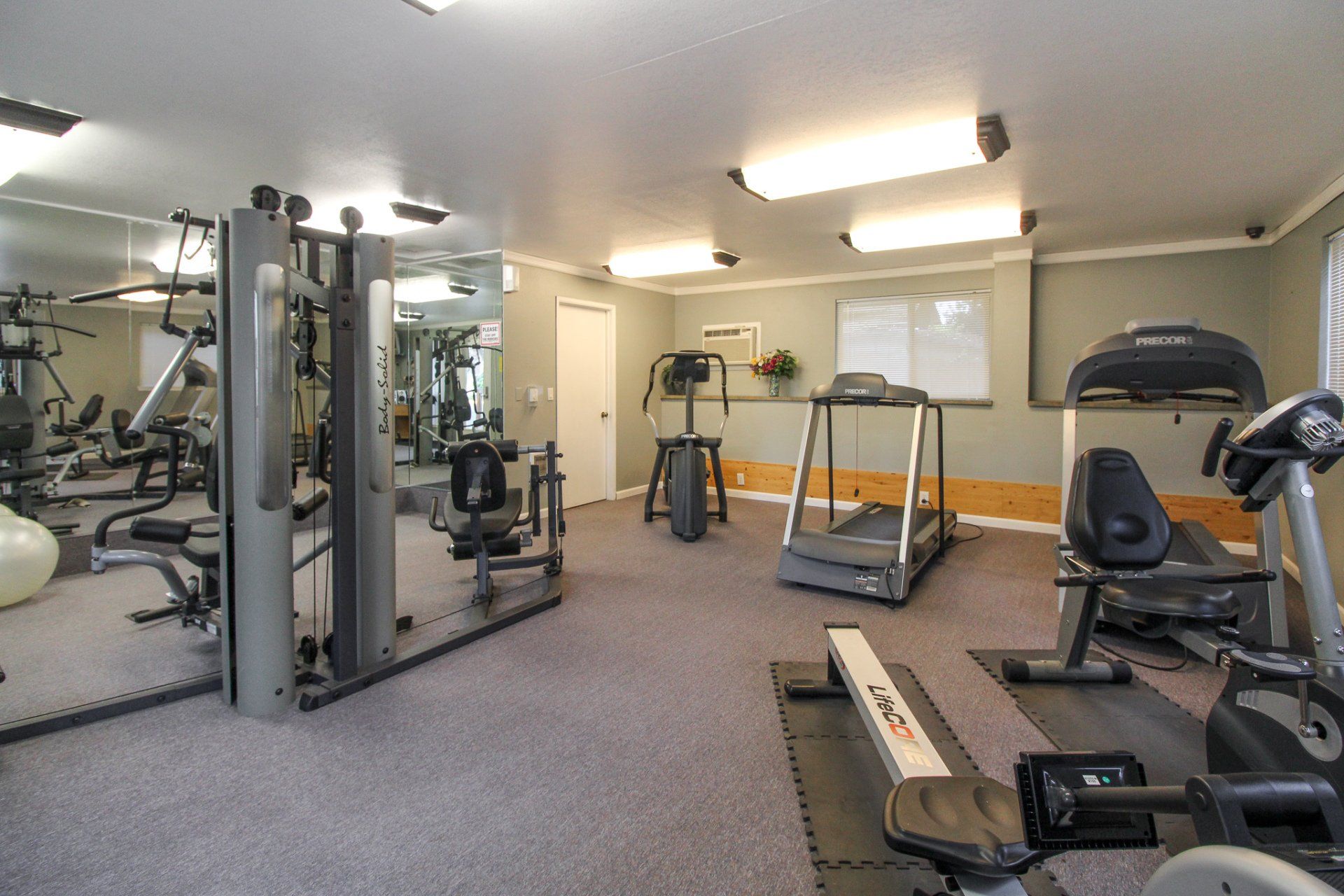 A gym with a lot of equipment including treadmills and exercise bikes