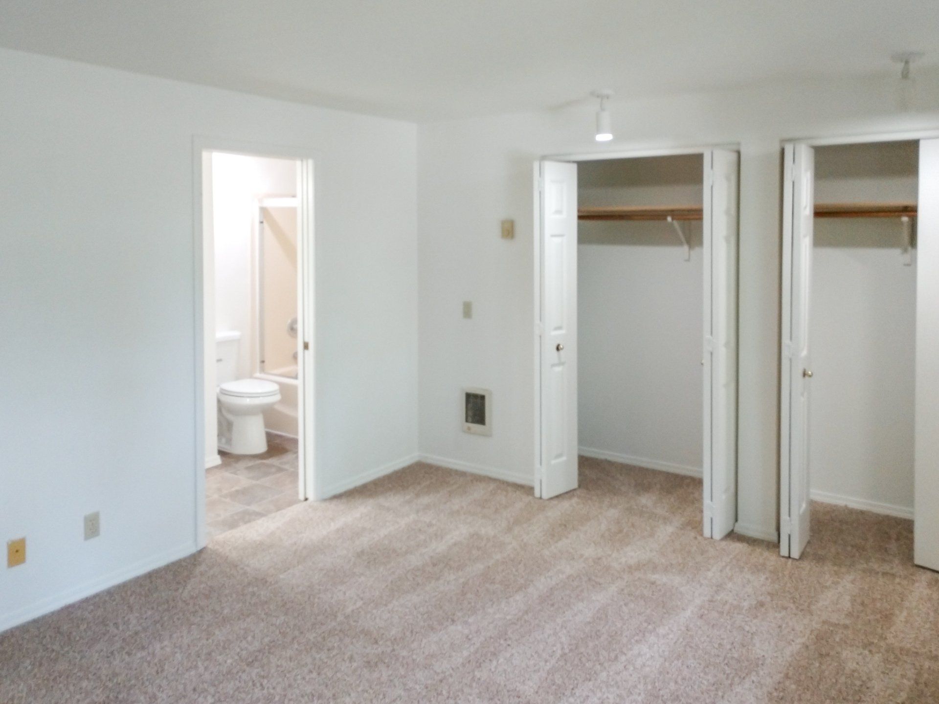 An empty bedroom with a toilet and closets