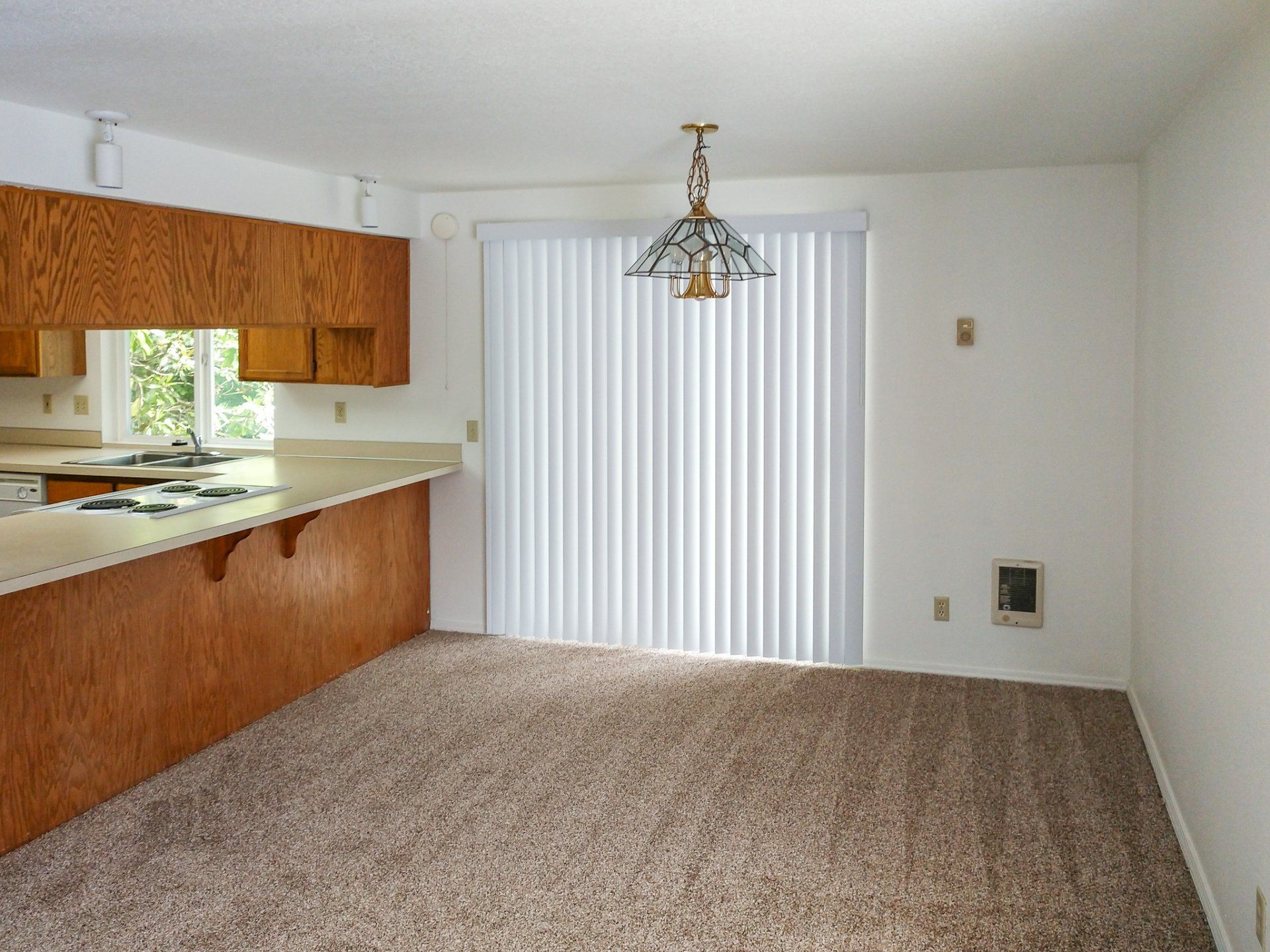 An empty kitchen with wooden cabinets and a sliding glass door