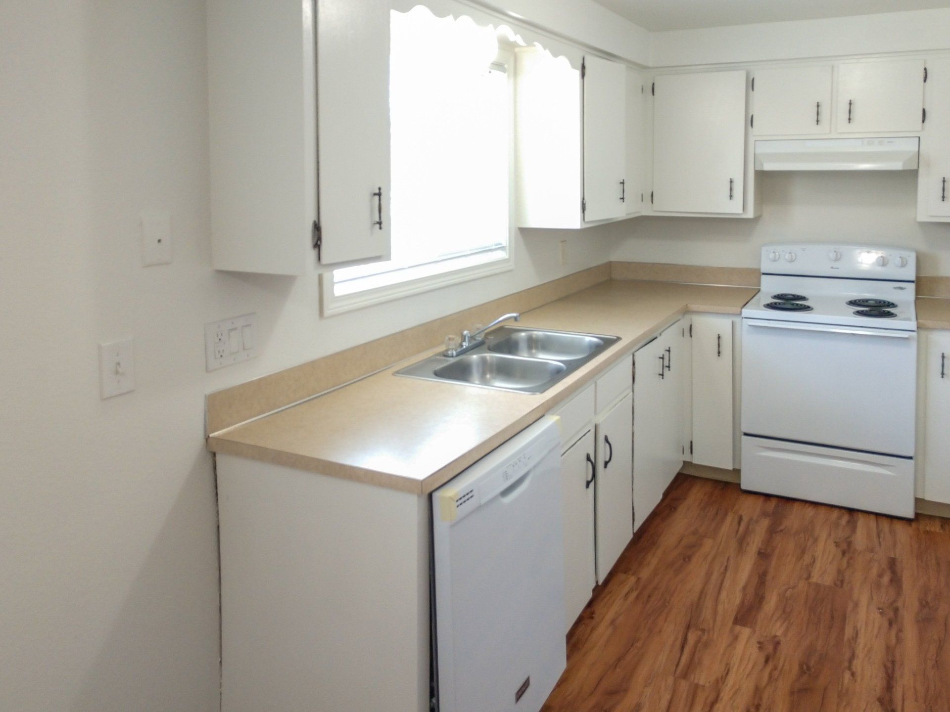 A kitchen with white cabinets and hardwood floors