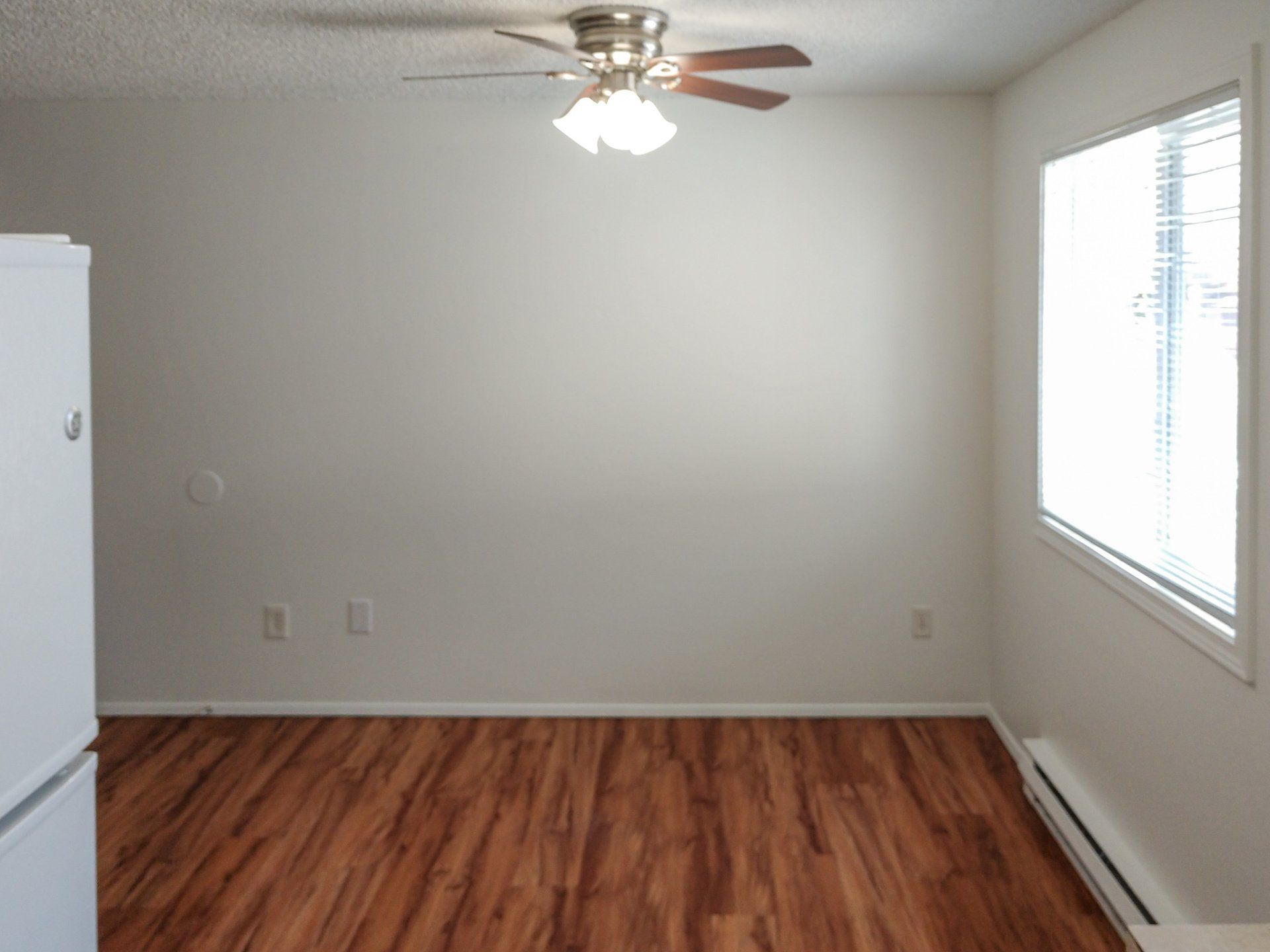An empty room with hardwood floors and a ceiling fan