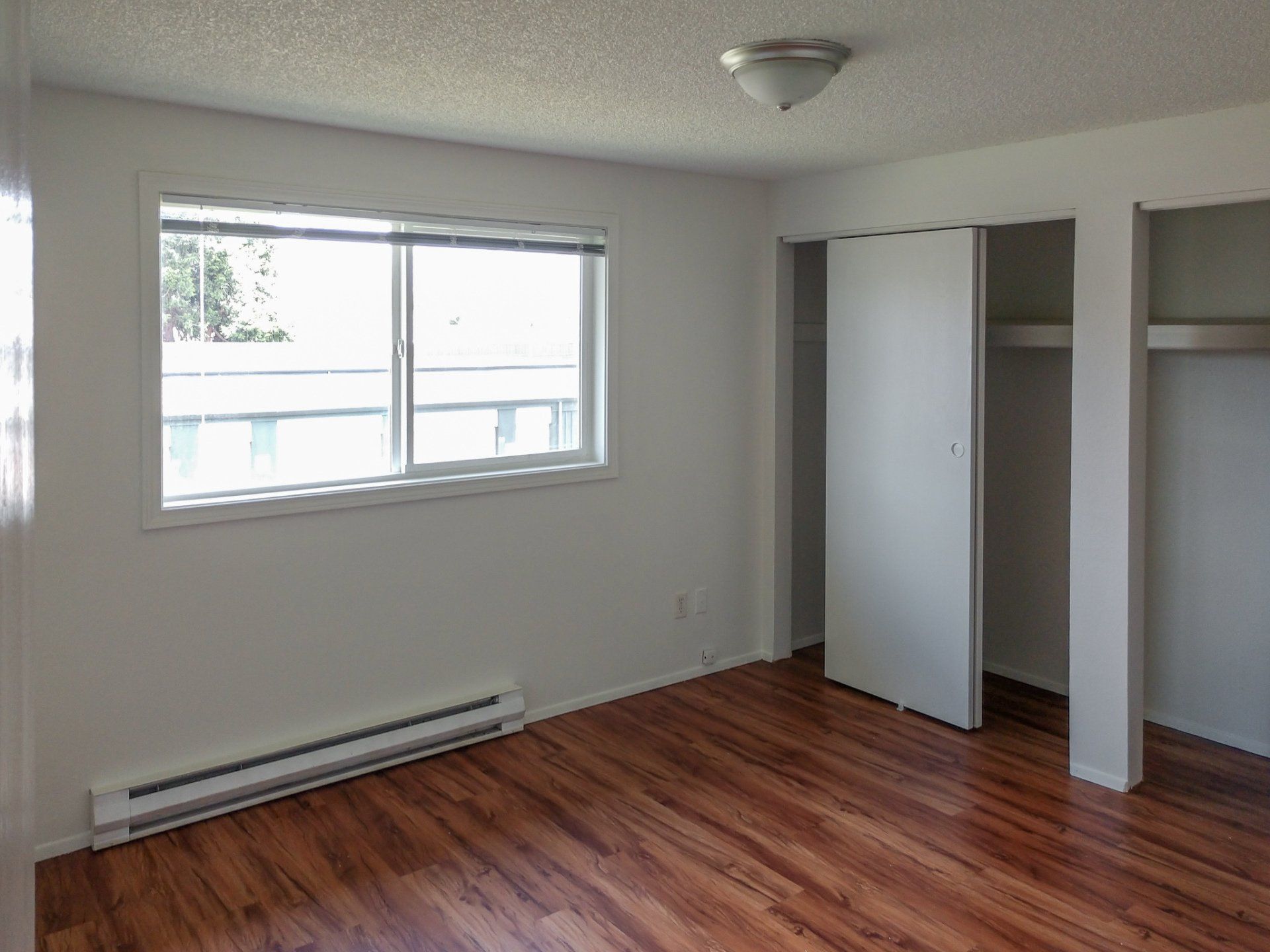 An empty room with hardwood floors and a window