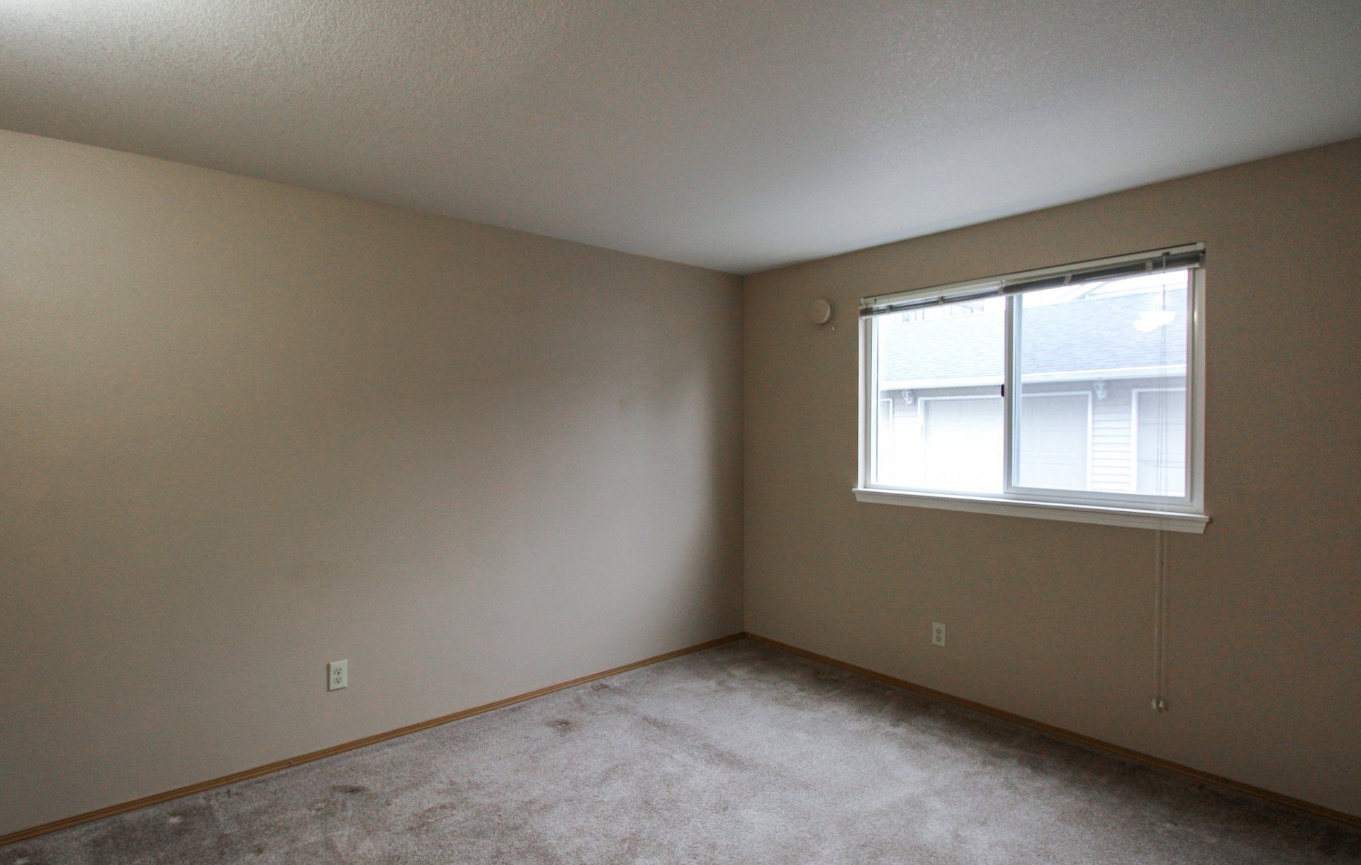 An empty bedroom with a sliding glass door and a window.