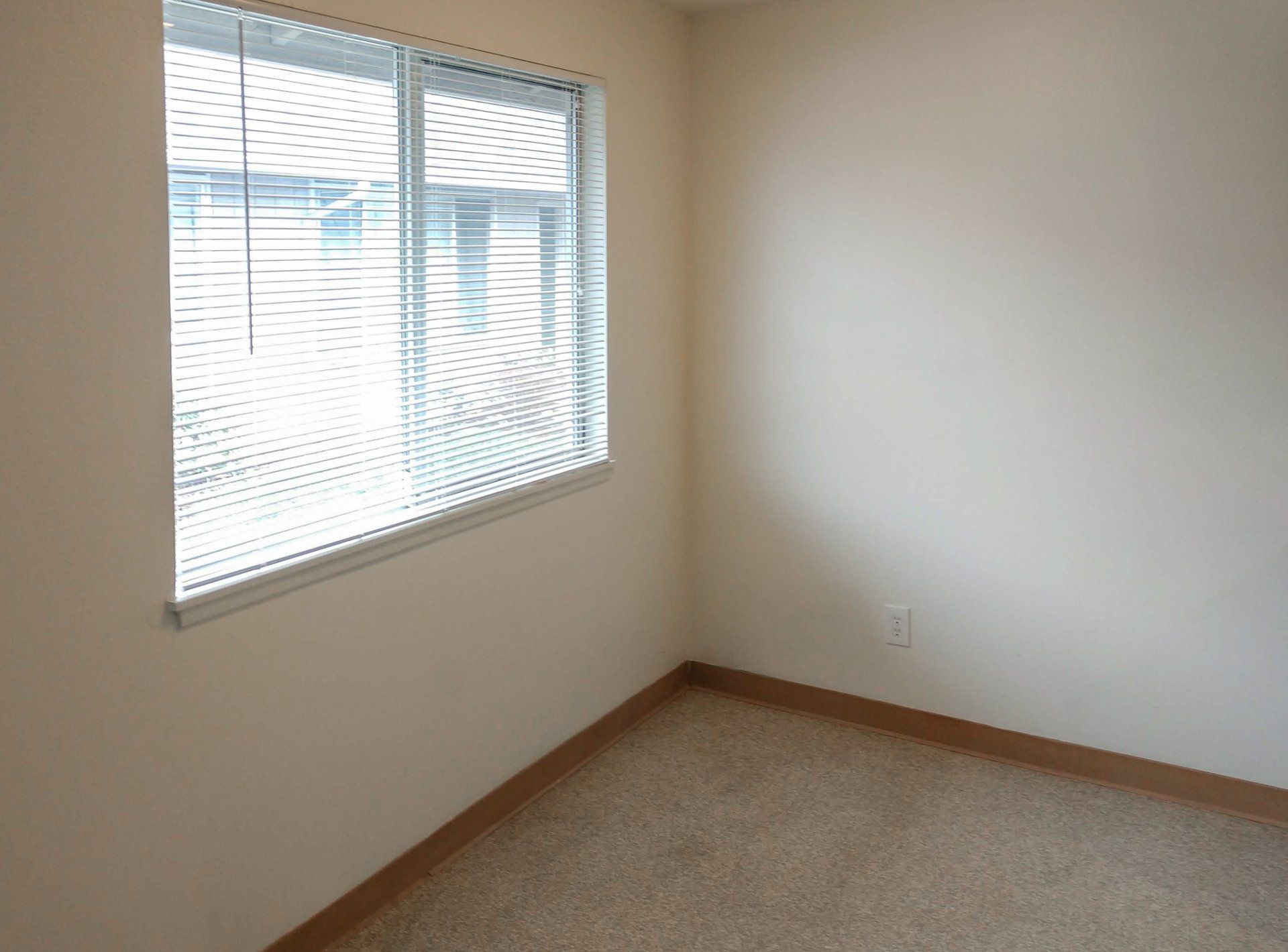 An empty room with a window and blinds on it