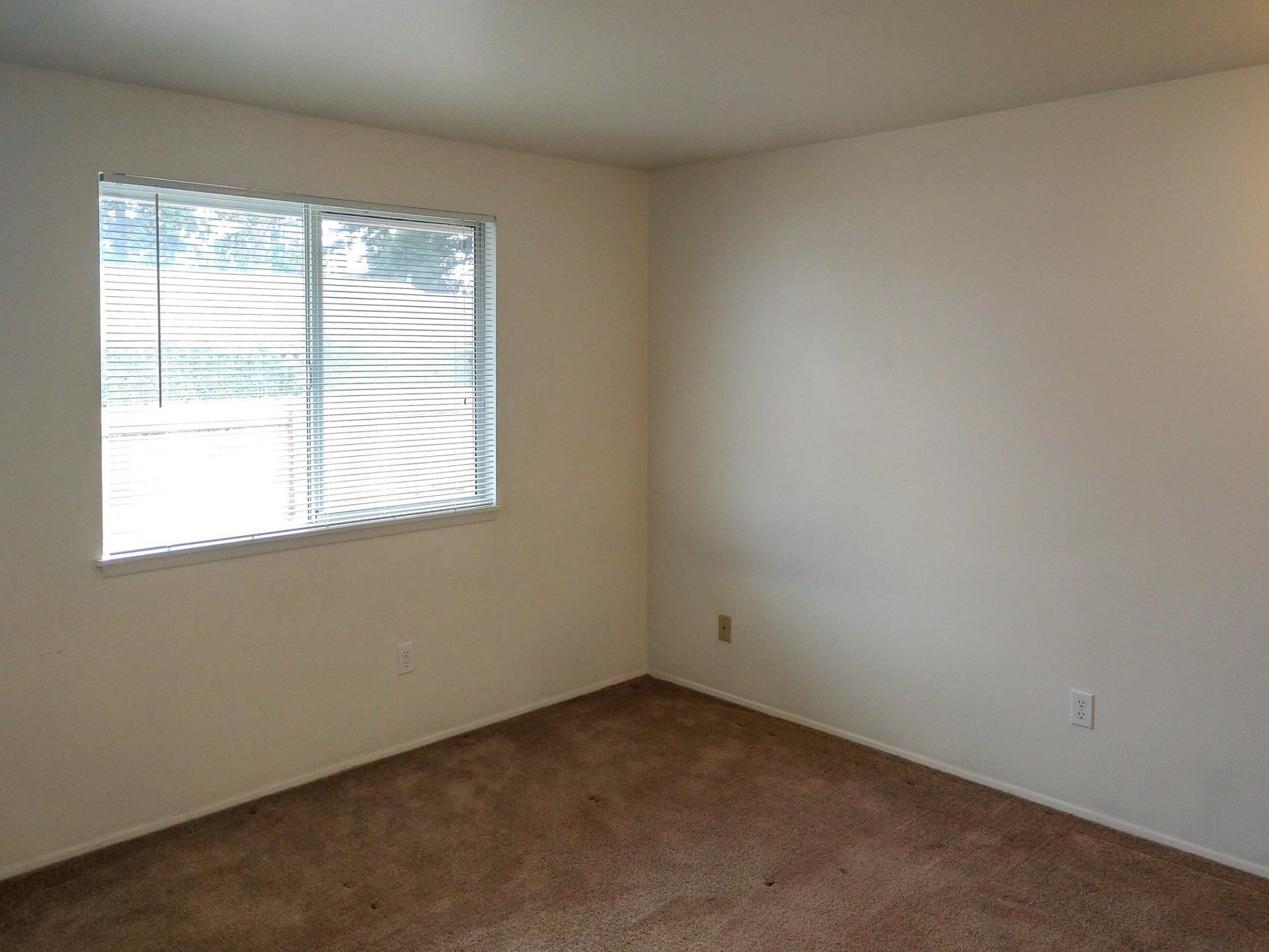 An empty bedroom with a sliding glass door and a window.
