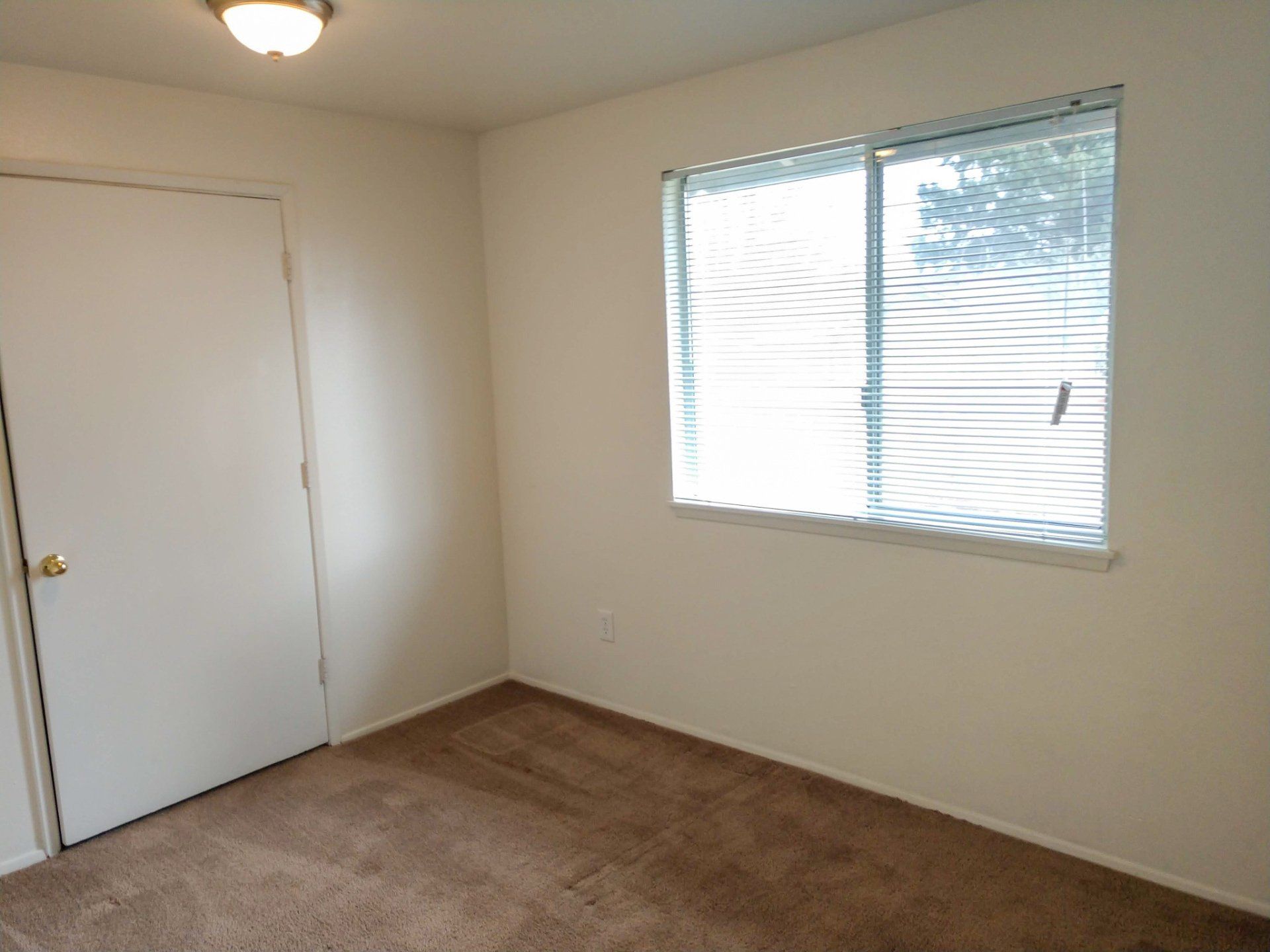 An empty bedroom with a window and blinds