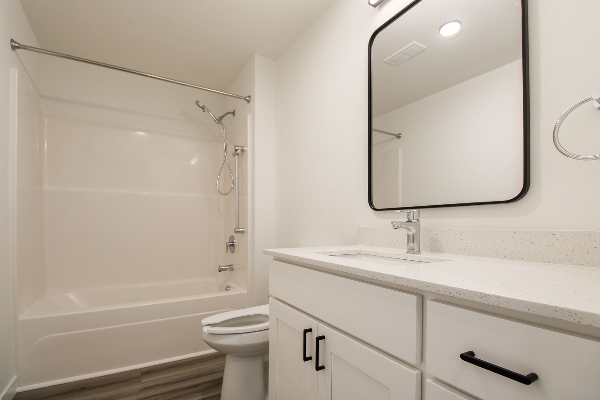 A bathroom with a sink , toilet , shower and mirror.