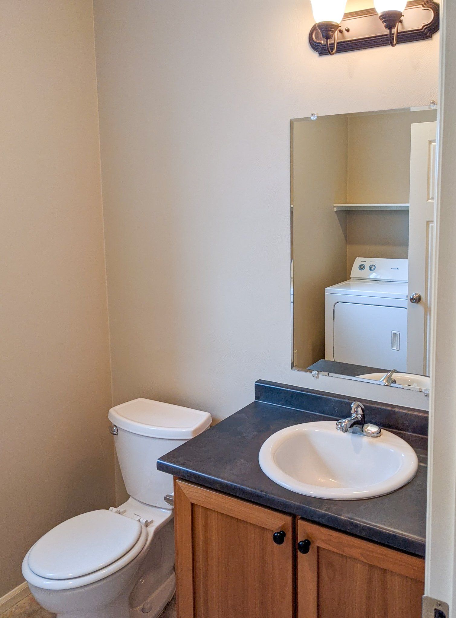 A bathroom with a toilet , sink and mirror.