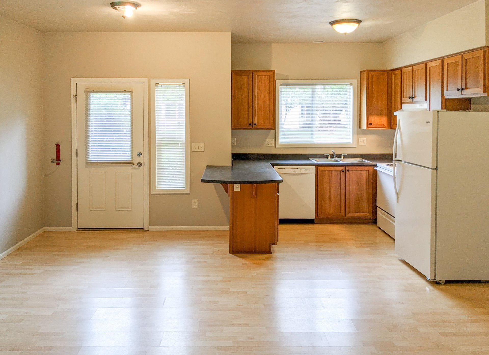 An empty kitchen with wooden cabinets and a white refrigerator
