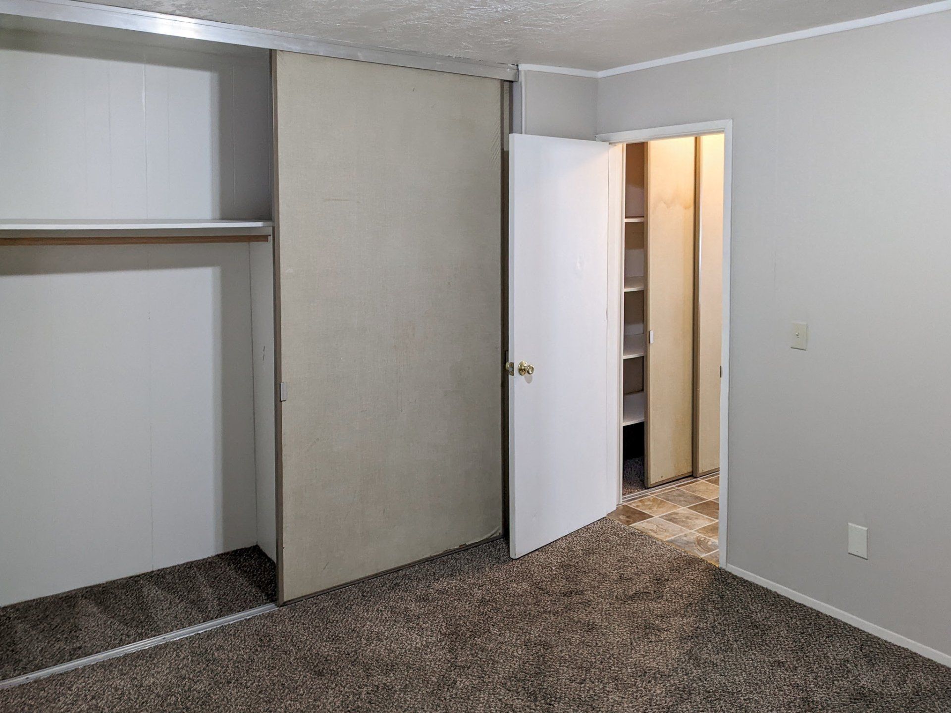 An empty bedroom with a closet and a mirror.