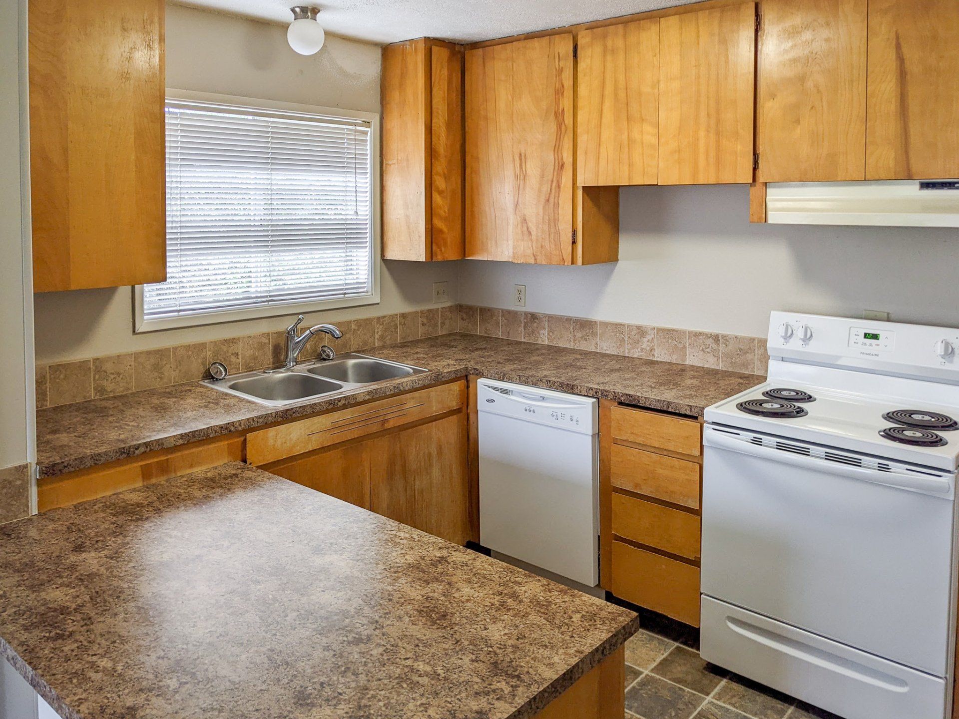 A kitchen with a stove , sink , and dishwasher