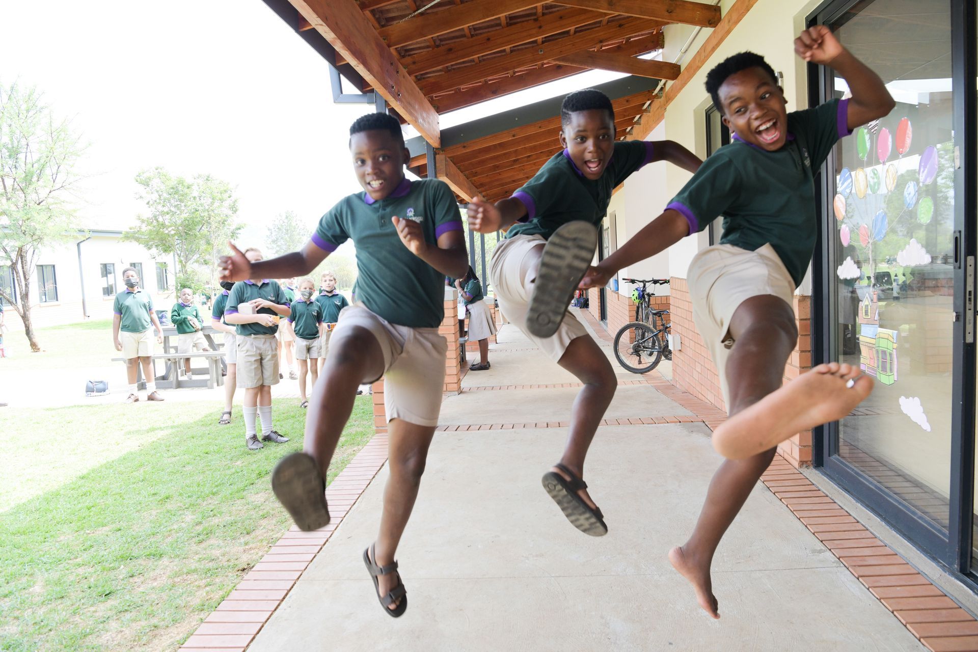 three young boys are jumping in the air in front of a building .
