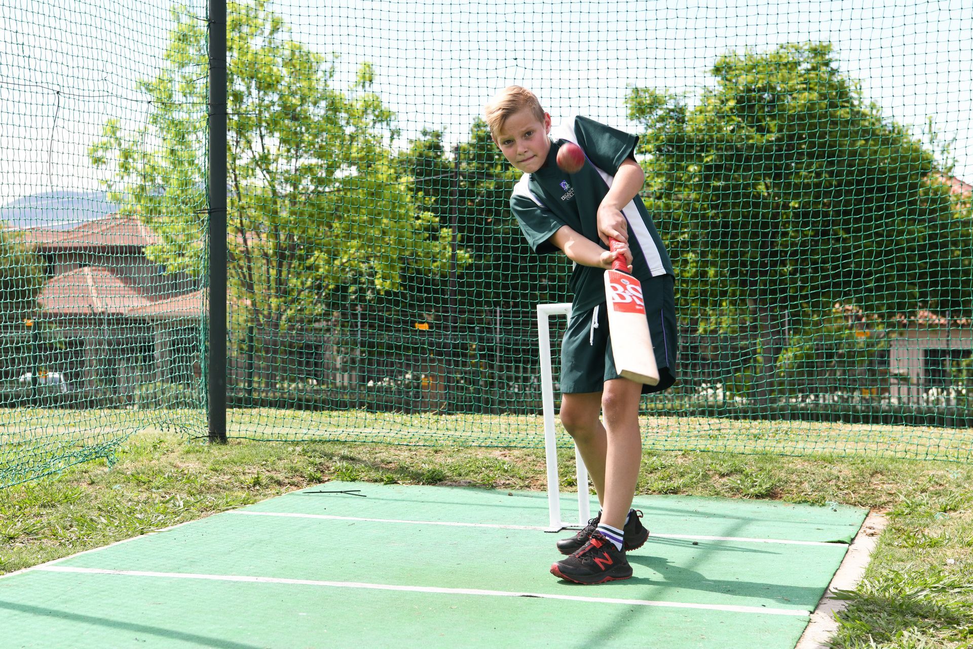 a young boy is holding a cricket bat and a ball .