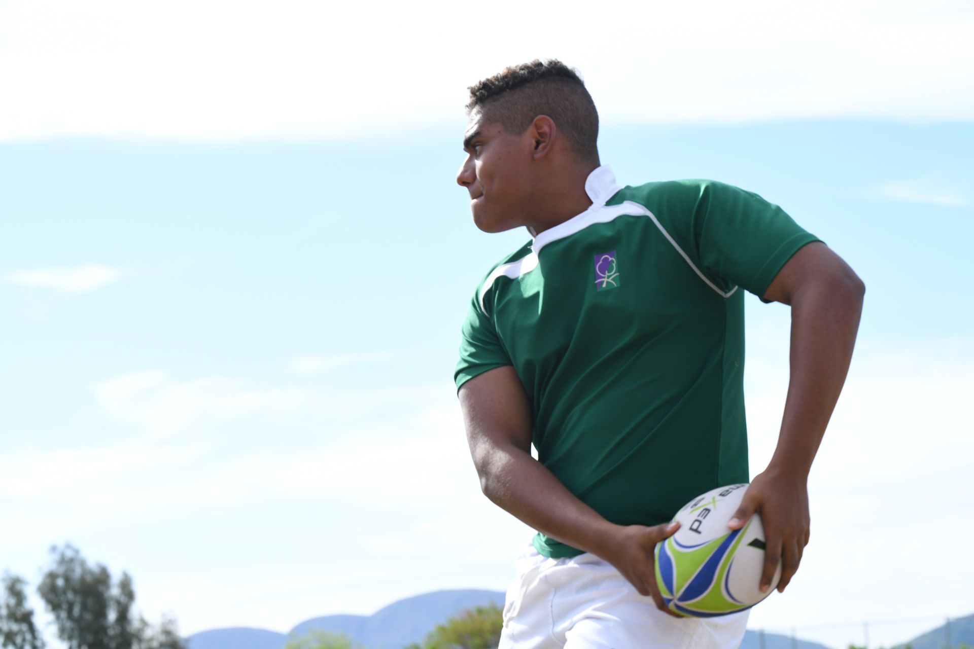 a boy in a green shirt is holding a rugby ball