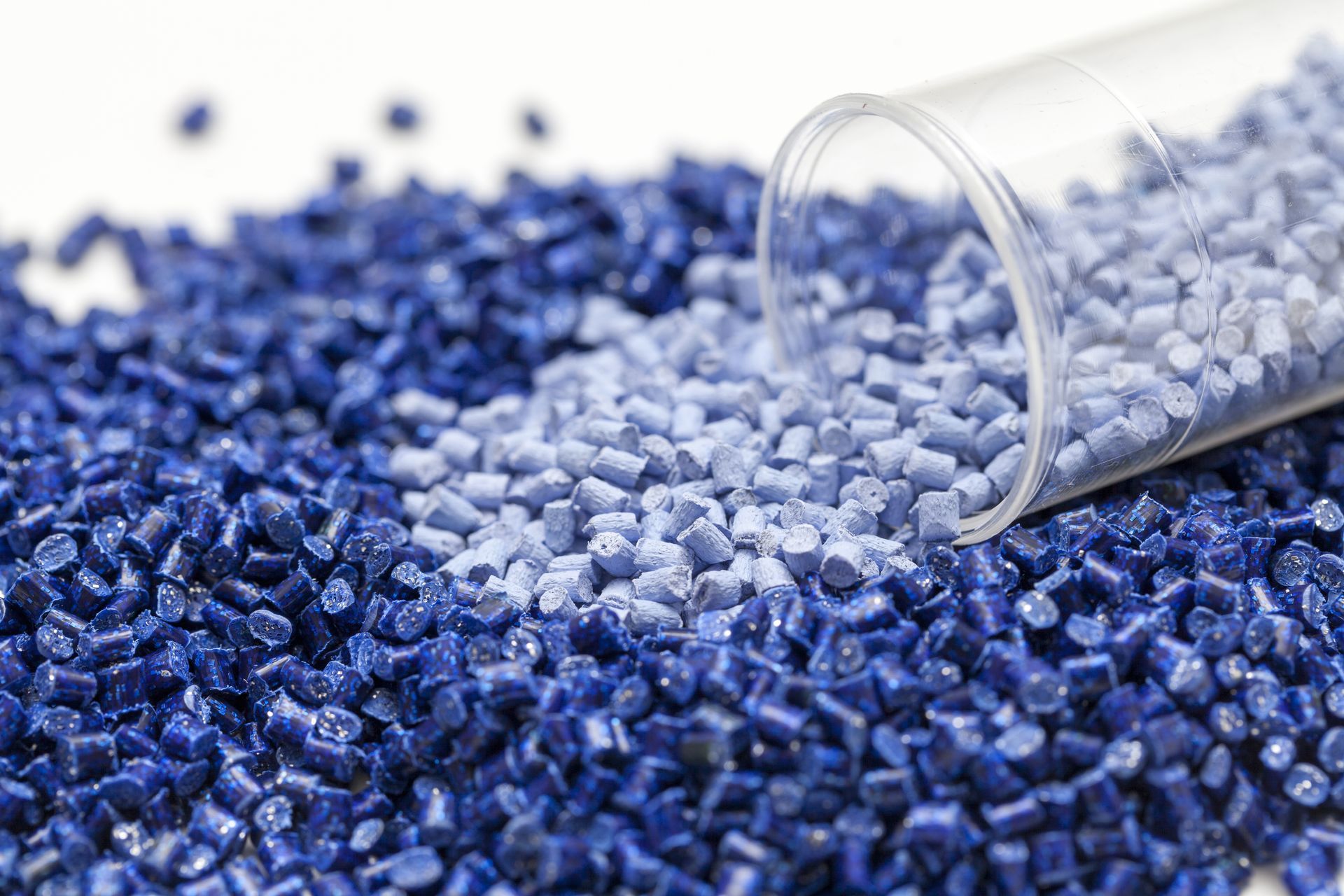 Blue plastic pellets spilling from a clear tube.
