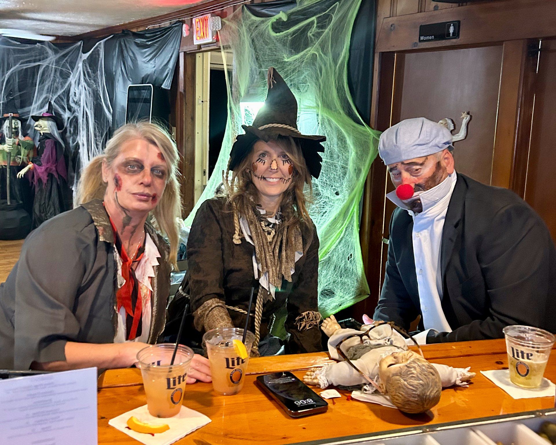 A group of people dressed in halloween costumes are sitting at a bar.