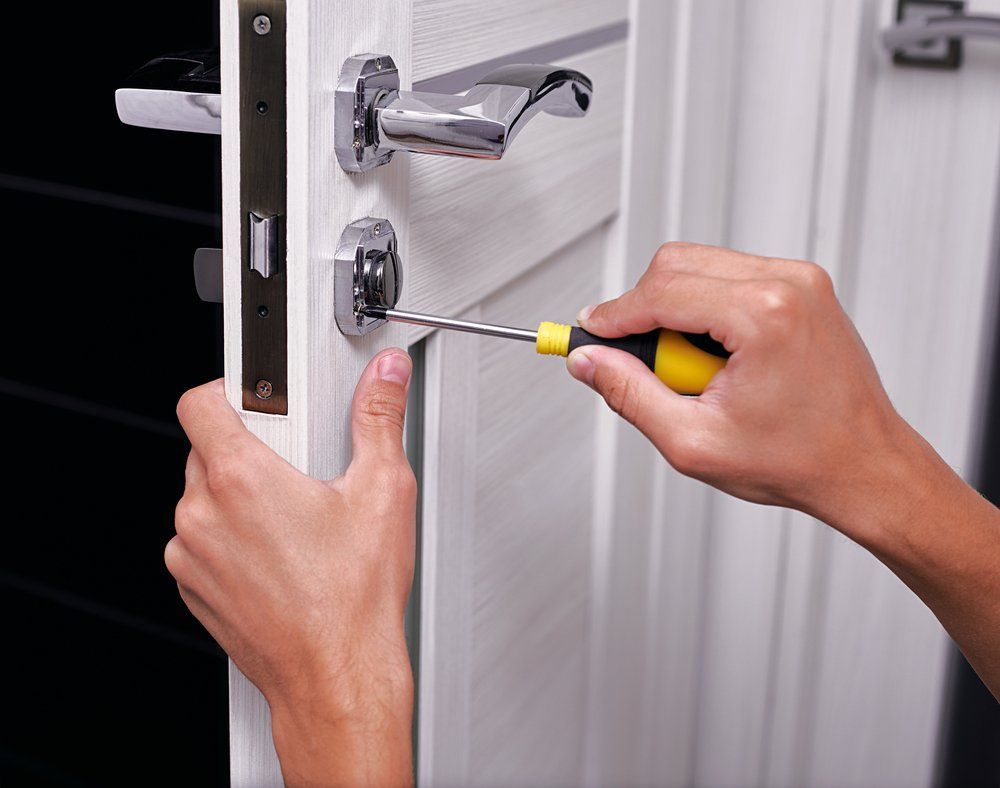 A Person Is Fixing A Door With A Screwdriver — Grafton Locksmith Service In Grafton, NSW