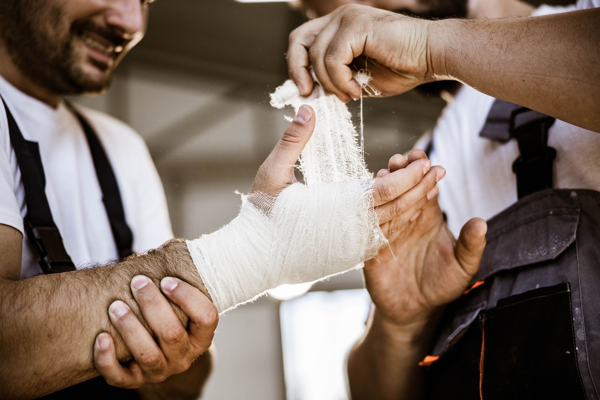 A man is putting a bandage on another man 's hand.