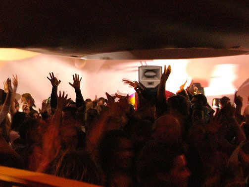 The club dance floor is filled with an excited crowd under vibrant sound