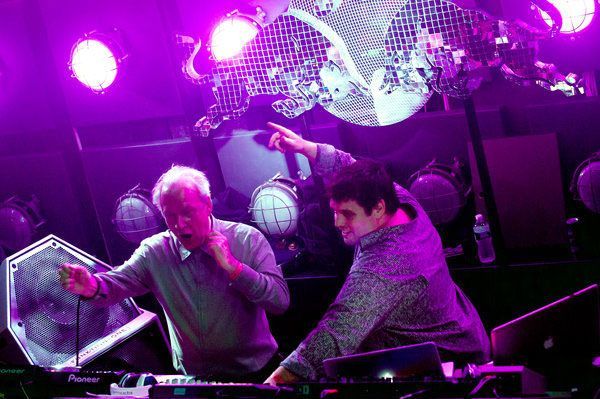 DJs performing live in a nightclub under neon lights and disco decor