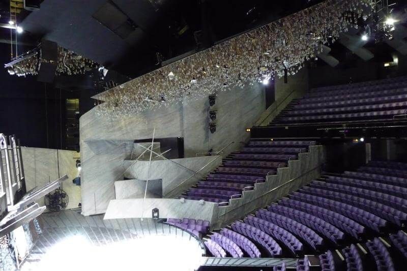 Contemporary theater with tiered purple seating and a spotlighted stage.