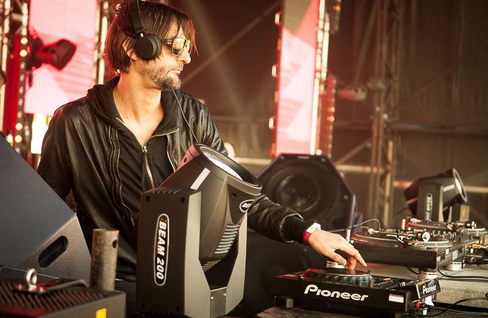 DJ performing with turntables and Beam 200 lights on an outdoor stage.