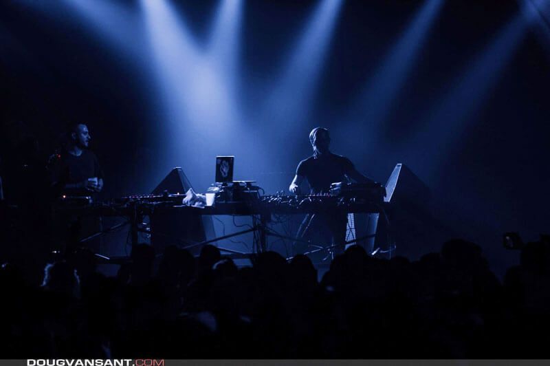 DJs performing live on stage with dramatic blue lighting and a crowd