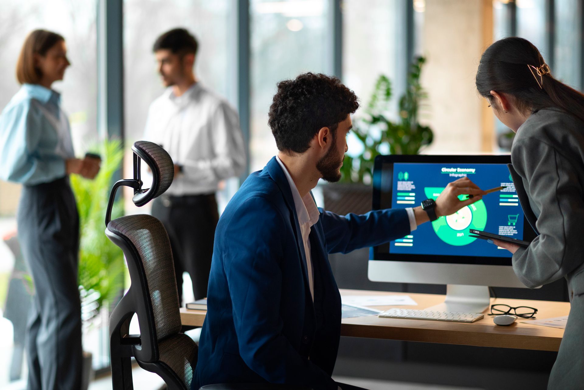 Zakelijke collega's bekijken grafieken op een computerscherm in een kantooromgeving.