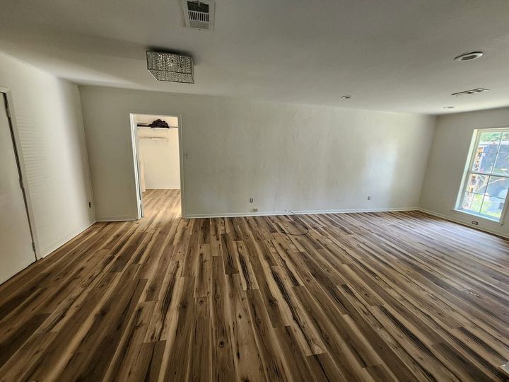Empty room with wood-patterned floor, white walls, and a doorway leading to a hall.