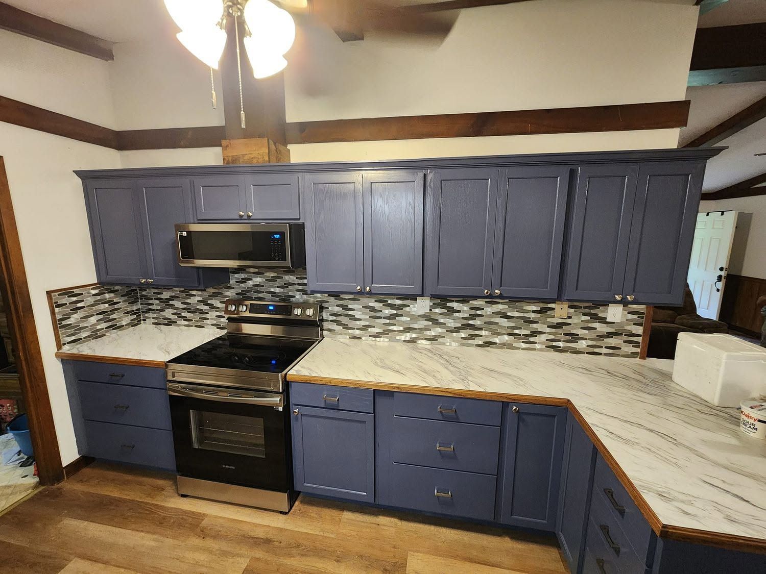 Blue kitchen with stainless steel stove, patterned countertops, and a ceiling fan above.
