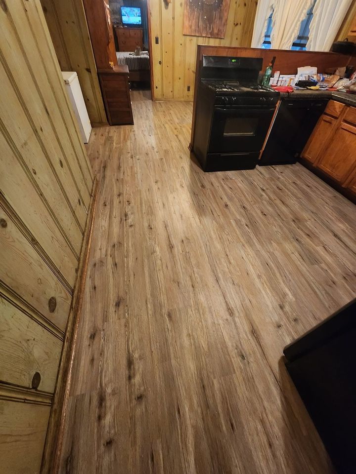Narrow kitchen hallway with wood floors, cabinets on both sides, and a stove and sink on the right.